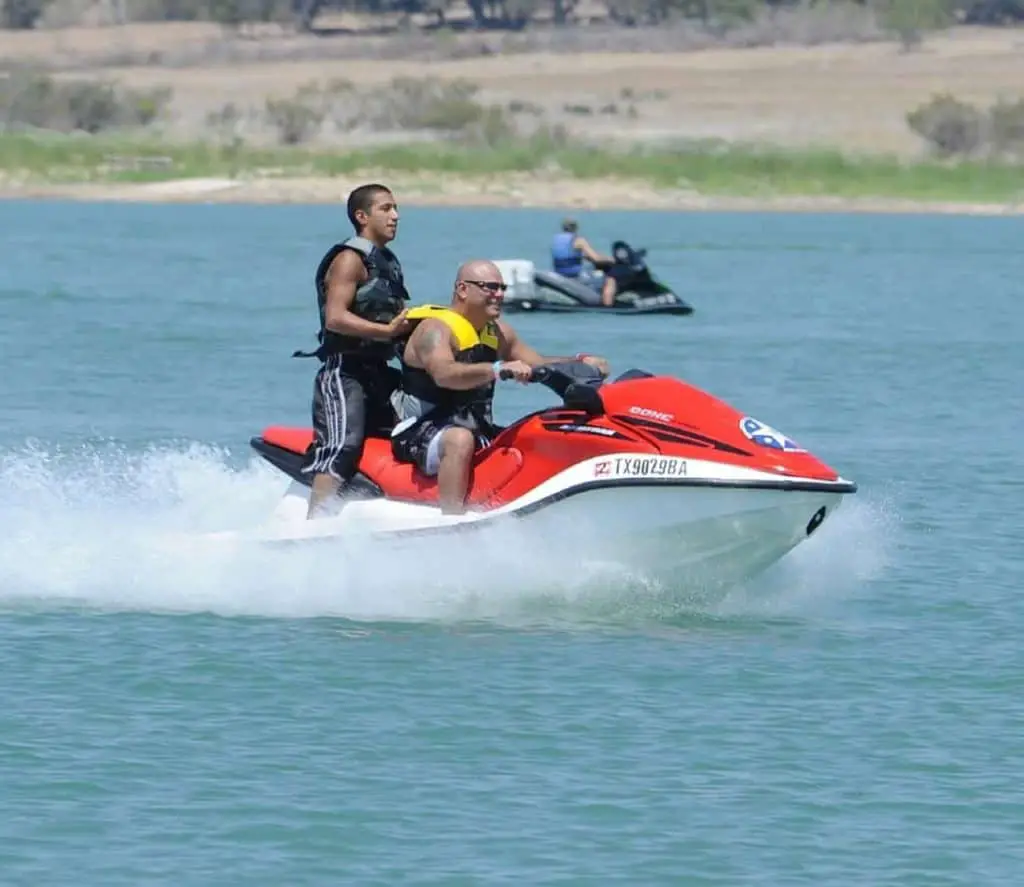 Demuestra a un pasajero montando una moto de agua mientras está de pie